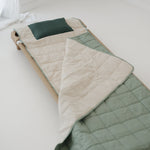 A olive green and beige stripe quilted daycare bedding nap mat with a dark green pillowcase attached. It has a built in matching pillowcase, pillow insert, name tag and carry handle. The daycare bedding nap mat is laid out on a daycare stacker bed frame against a white background.