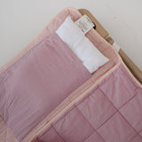 A soft purple and dusty pink stripe quilted daycare bedding nap mat with a soft peach underside on quilt. It has a built in matching pillowcase, pillow insert, name tag and carry handle. The daycare bedding nap mat is laid out on a daycare stacker bed frame against a white background showing the removable pillow insert.