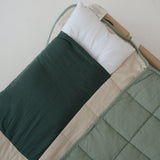 A olive green and beige stripe quilted daycare bedding nap mat with a dark green pillowcase attached. It has a built in matching pillowcase, pillow insert, name tag and carry handle. The daycare bedding nap mat is laid out on a daycare stacker bed frame against a white background showing the pillow insert that is included.