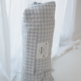 A light blue and white gingham quilted daycare bedding nap mat with soft yellow on the underside of the blanket. It has a built in matching pillowcase, pillow insert, name tag and carry handle. The daycare bedding nap mat is rolled up showing how it is packed away not in use and photographed against a white background.