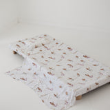 A white and multicolour bohemian style mermaid sheet set laid out onto a daycare stacker bed. The print features hand painted mermaids of different tones, with various colour tails and hair colours including soft blue, soft purple and soft pink. The mermaids have flowers in their hair and hands with same flowers scattered throughout. The products are photographed with a white background.