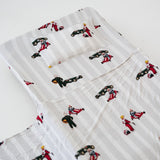 A white and soft grey striped daycare sheet set laid out onto a daycare stacker bed. The print features vintage hand drawn boys dressed in vintage race overalls and helmet next to a vintage race car and driving a vintage go kart. The products are photographed with a white background.