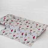 A white and soft grey gingham daycare sheet set laid out onto a daycare stacker bed. The print features vintage hand drawn farm animals including chickens, pigs, little girl walking a horse, a boy pushing his dogs in a wheelbarrow, red barn and cows eating hay out of a tractor and trailer. The products are photographed with a white background.