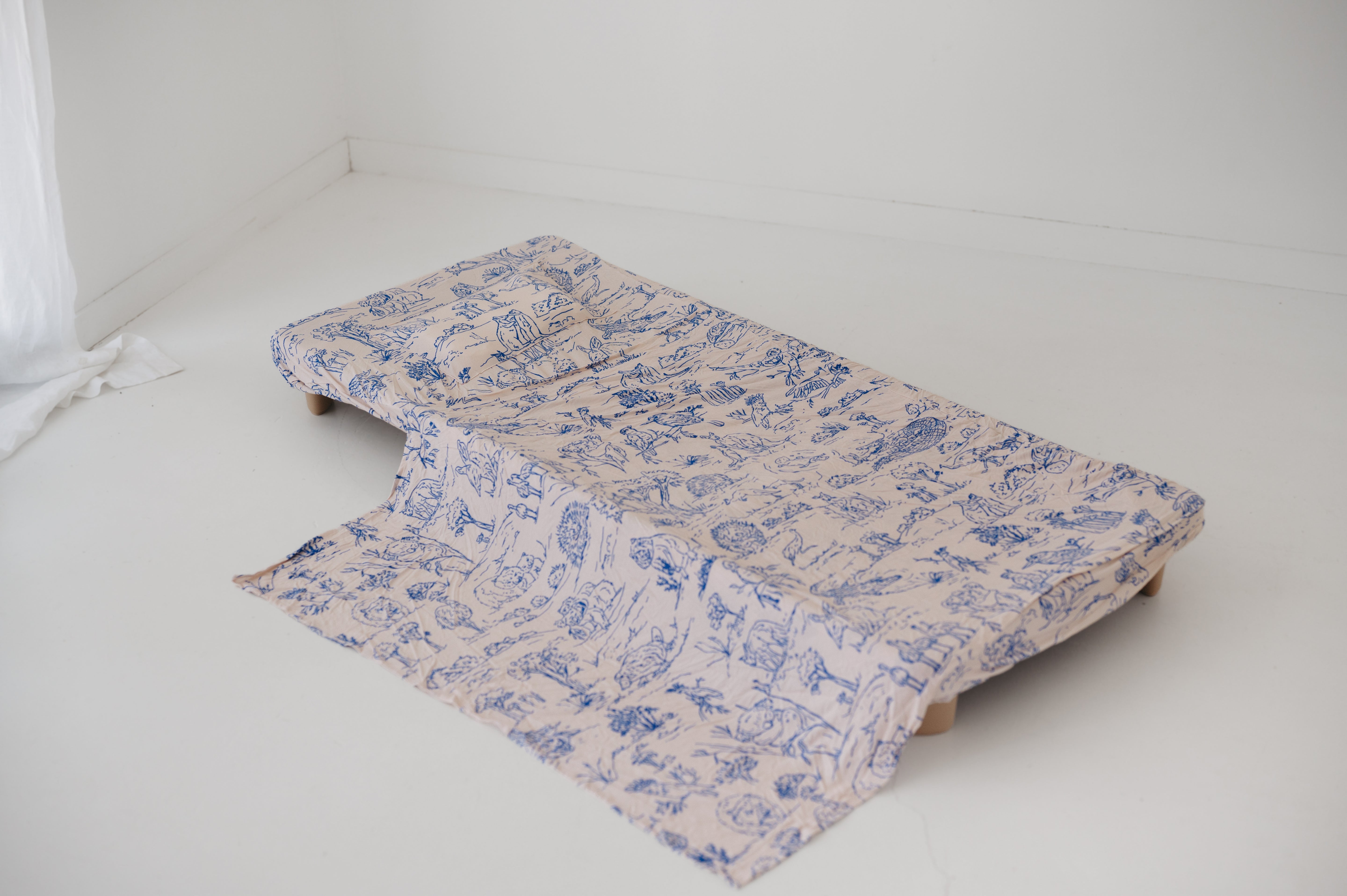 A soft beige and blue daycare sheet set laid out onto a daycare stacker bed. The print features hand drawn outback Australian animals and natives including emu's, crocodiles, kangaroos, koala's, wombats, echidna's with native gum trees and plants. The products are photographed with a white background.
