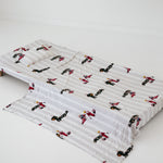 A white and soft grey striped daycare sheet set laid out onto a daycare stacker bed. The print features vintage hand drawn boys dressed in vintage race overalls and helmet next to a vintage race car and driving a vintage go kart. The products are photographed with a white background.