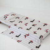 A white and soft grey striped daycare sheet set laid out onto a daycare stacker bed. The print features vintage hand drawn boys dressed in vintage race overalls and helmet next to a vintage race car and driving a vintage go kart. The products are photographed with a white background.