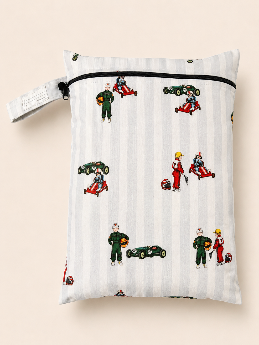 A rectangle PUL fabric daycare wet bag  with a zipper closure and a button loop strap, printed with a hand vintage racing pattern on a light grey and white stripe background. The print includes a boy in a vintage go kart, boy in a green race suit and a vintage race car. Photographed on a soft a beige background.